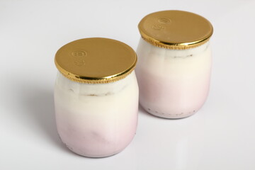 Yogurt in small glass jar with aluminum foil seal cap. Isolated