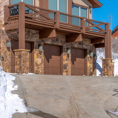 Square Home facade with three car garage amid snowy ground on a sunny winter day