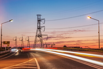 New highway and high-voltage towers at sunset time.