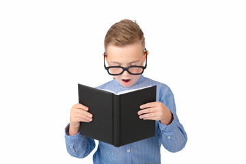 Cute dreamy schoolboy reads book and wearing glasses while standing in the studio, isolated over white