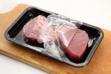 Raw tuna steak in disposable plastic packing box