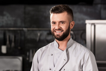 Chef at kitchen restaurant. Portrait of smiling chef at professional kitchen.