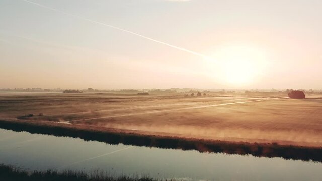 Aerial shot of the rural dutch countryside with fog at sunrise, Netherlands. Water and dikes with birds. High quality FullHD footage