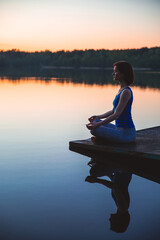  Woman exercising yoga pose vital and meditation for fitness lifestyle outside. sunrise on lake. nature background. Healthy and Yoga Concept. Peaceful lifestyle