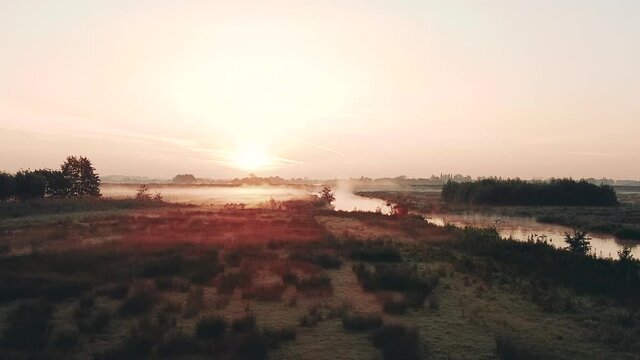 Aerial shot of the rural dutch countryside with fog at sunrise, Netherlands. Water and dikes with birds. High quality FullHD footage