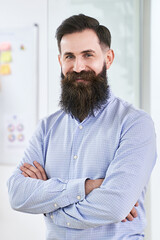 Portrait of a happy smiling bearded senior developer or manager in modern IT office.