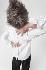 Androgyne in white shirt worn reverse side moving strangely with her hands at the back. Isolated...
