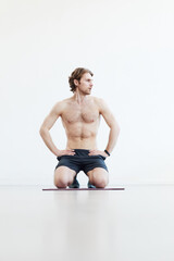 Obraz premium Young muscular man sitting on the floor and resting after training against the white background