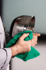 Hands wipe bowl with duster. Closeup chef hands with green duster.