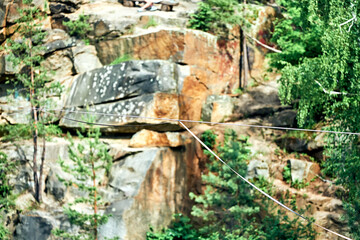 The rope along which people walk, cable walkers, is pulled between the canyon. Spring. Stone walls and green trees.