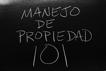 The words Manejo De Propiedad 101 on a blackboard in chalk.  Translation: Landlording 101