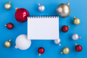 Christmas composition with  open notepad and colorful  balls on the  blue background. Copy space. Top view.