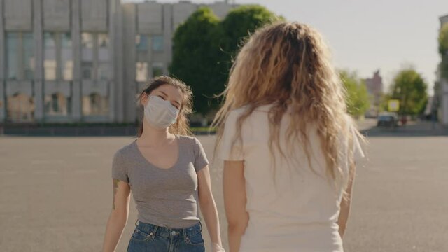 Social distancing. Friends in protective medical face mask greet their elbows. Elbow bump is new greeting to avoid spread of coronavirus or covid-19 - Avoid or Stop handshakes due to pandemic.