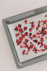 Gray baking sheet with parchment and baked pieces of beetroot. Homemade healthy chips.
