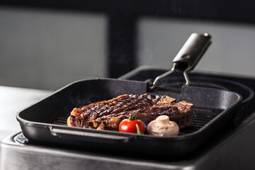 Hot steak at griddle pan. Closeup grill beef with tomato and mushroom at pan.