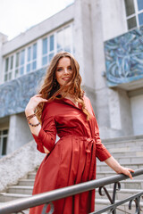 Fototapeta premium A girl in a red dress, standing on the stairs