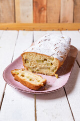 geschnittener, frischer Kuchen mit Rhabarber, Puderzucker und Eierlikör auf einem Tisch aus Holz in der Küche am Nachmittag