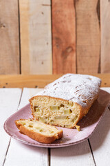 geschnittener, frischer Kuchen mit Rhabarber, Puderzucker und Eierlikör auf einem Tisch aus Holz in der Küche am Nachmittag