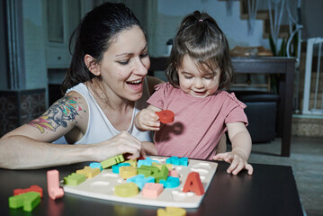 A mother teaching her daughter the letters of the alphabet