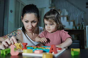 A mother teaching her daughter the letters of the alphabet