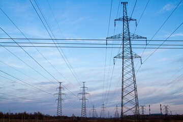 High voltage power lines in the middle of a field at sunset. Industrialization. Electrification. Power supply.