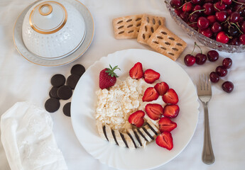 Sweet ripe strawberries and fresh cottage cheese on a white plate. Bright and healthy breakfast in the early morning