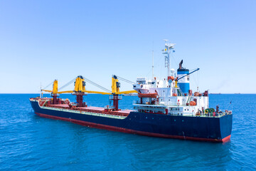 Large Cargo Ship with four Yellow cranes at sea, Drone footage.
