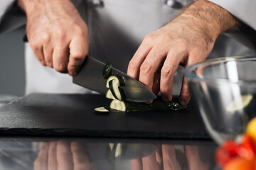 Male chef cutting fresh vegetable. Closeup chef hands with knife at kitchen.