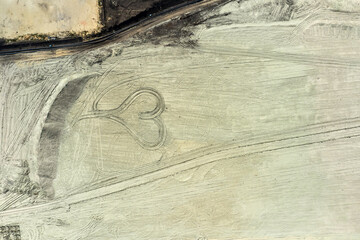 Top view on a heart drawn in quarry from coal. Heart from sand.