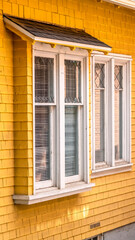 Fototapeta premium Vertical crop Building exterior with yellow wall cladding and awning over the window