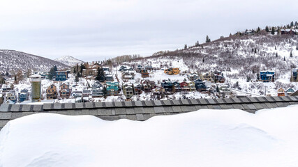 Panorama Gray snowy roof against colorful homes on frosted hill in Park City Utah