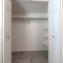 Square crop Walk in closet with double hinged doors plain white wall and gray floor carpet