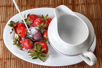 Strawberries are poured with cream on a tray with milk jug