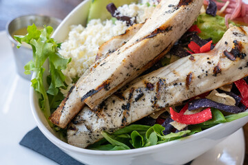 grilled chicken in selective focus on a salad with cheese and multicolored tortilla strips