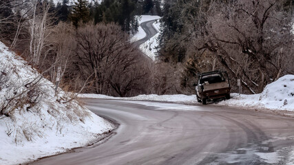 Panorama Road winding through snowy mountain with leafless trees and evergreens in winter