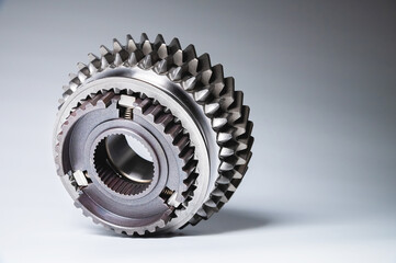 The new shiny metal gear of the switch box is fronted by a gray gradient background. The concept of new spare parts for car maintenance and repair