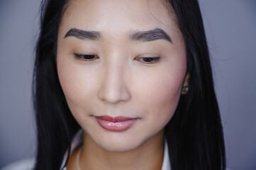 Obraz premium Portrait of a beautiful asian woman during eyelash extension procedure. Double eyelash volume before and after.