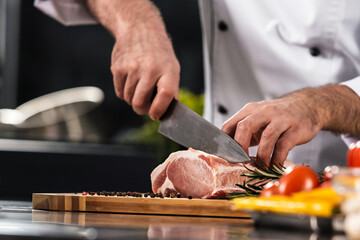 Chef hands with knife cut beef at kitchen. Closeup chef man hands cut meat. © stockbusters