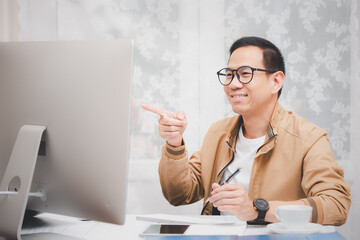 Asian man Talking and using laptop communicates on the internet with the customer. concept work from home.