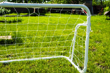 Mini football goal on the green grass on a plot near the house. Family play
