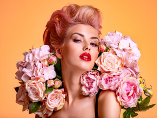 Beautiful white girl with flowers. Stunning blonde girl with big bouquet flowers of roses. Closeup face of young beautiful woman with a healthy clean skin. Pretty woman with bright makeup