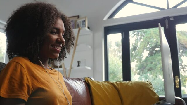 Mixed race woman on video call at home on the sofa