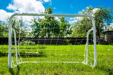 Mini football goal on the green grass on a plot near the house. Family play