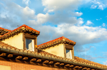 View of rooftop and sky with clouds at sunset. Roof tiles