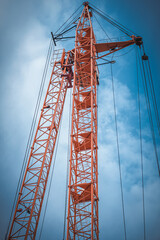 Fototapeta na wymiar Construction crane orange on a blue sky background. Bottom view.