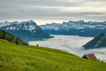 Gordijnen Clouds covering lakes below majestic Alpine peaks as seen from small meadow above the Sattel © Michal
