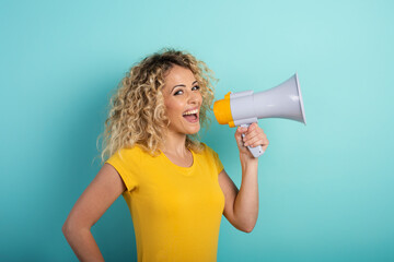 Woman speaks with loudspeaker. joyful expression. cyan background