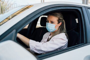  Woman with face mask driving her car during coronavirus pandemic