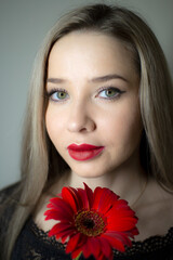 Fototapeta premium Portrait of a girl with a red gerbera flower.