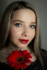 Portrait of a girl with a red gerbera flower.